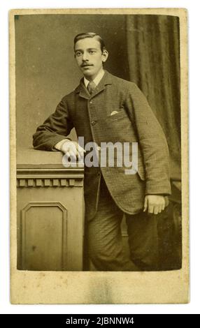 Original Victorian CDV  (Carte de Visite / visiting card) of attractive confident looking young man, late teens maybe, sparse moustache. He is wearing a tweed suit, with handkerchief pocket detail on the front (appears on men's suits in 1880), 4 in hand tie, short hair and a moustache. From the studio of William Towert & Son, 42 St. Patrick Square, Edinburgh, circa 1880. Stock Photo