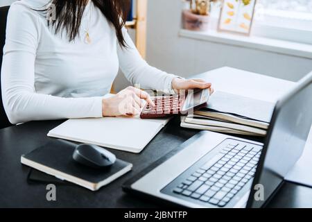 Account balance definition. Female Accountant working with laptop and calculator in office. Stock Photo