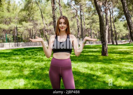 Cute caucasian woman wearing sportive clothes on city park, outdoors clueless and confused with open arms, shrugging shoulders, no idea and doubtful f Stock Photo