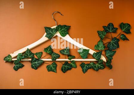 Hangers entwined with plants on background with copy space.Conscious and environmentally friendly consupmtion in shopping.Recycling or zero waste Stock Photo