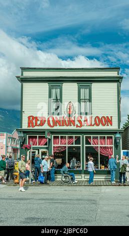 Skagway, Alaska, USA - July 20, 2011: Closeup of Green painted Red Onion Saloon facade under blue cloudscape. Giant red letters and logo on building. Stock Photo