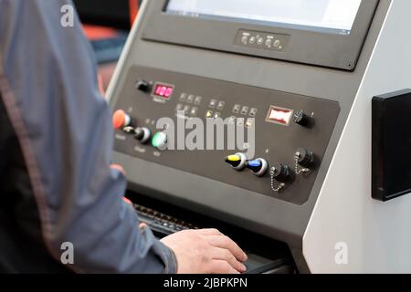 Worker controls metalworking CNC machine. Selective focus. Stock Photo