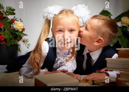 Girl and boy who is elementary school children in uniform having fun with book. Brother and sister on September 1 in Russia. Schoolgirl and schoolboy Stock Photo