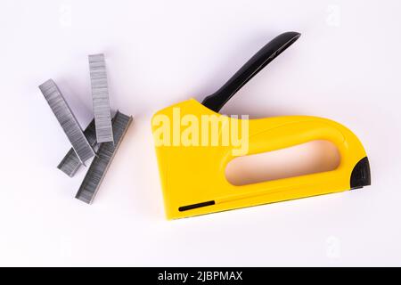 Yellow staple gun and metal staples on a white background. Stock Photo