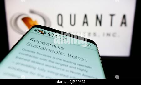 Mobile phone with website of American infrastructure company Quanta Services Inc. on screen in front of logo. Focus on top-left of phone display. Stock Photo