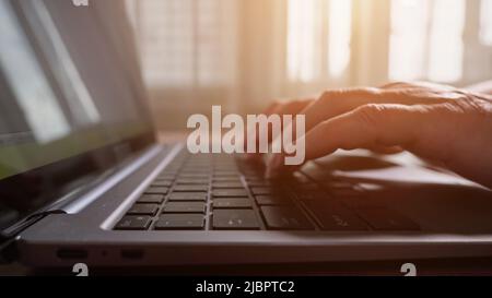 Female wrinkled fingers touch black keys of laptop keyboard Stock Photo