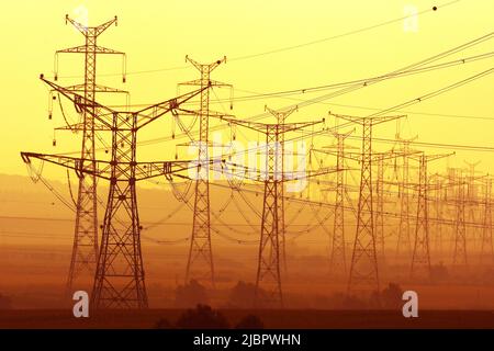 Electricity pylons at sunset Stock Photo