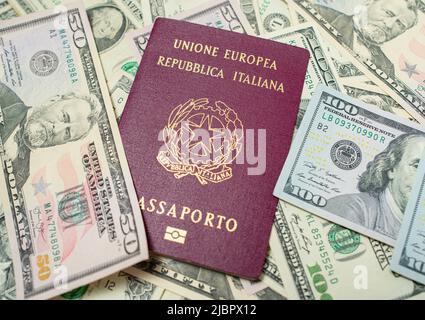 Italian Passport on top of dollar banknotes. One hundred and fifty USD bills. European Union Passport. Traveling to the United States. Stock Photo