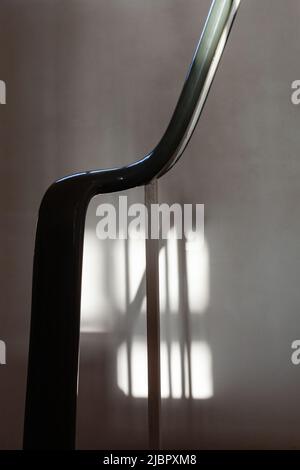 Retro hand rail casting a shadow on the wall of the landing midway up the duplex. Stock Photo