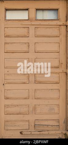 Front view of an old and weathered wooden door painted in beige or light brown. Abstract high resolution full frame textured background. Stock Photo