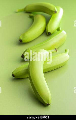 Unripe green bananas on a green table. Stock Photo