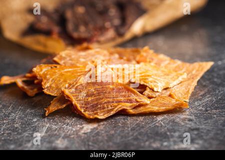 Turkey jerky meat. Dried sliced meat on a black table. Stock Photo
