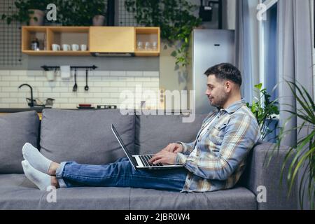 Man at home working sitting on sofa remotely with laptop Stock Photo