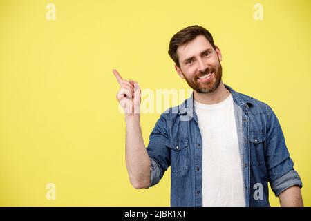 Smiling man with beard raising his finger up and pointing to empty space Stock Photo