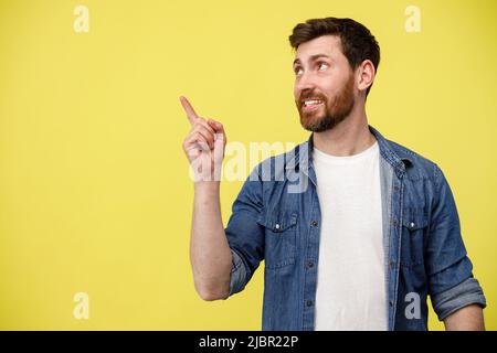Smiling man looking at side with raising his finger up and pointing to empty space Stock Photo