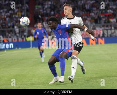 Munich, Germany. 7th June, 2022. Germany's Nico Schlotterbeck (R) vies with England's Bukayo Saka during their UEFA Nations League A football match at the Allianz Arena in Munich, Germany on June 7, 2022. Credit: Philippe Ruiz/Xinhua/Alamy Live News Stock Photo