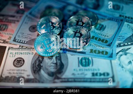 Gold Bitcoins on hundred Dollar Banknotes from USA. United States of America Currency with Cryptocurrency Bitcoin. Illuminated by Blue light Stock Photo