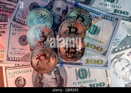 Gold Bitcoins on hundred Dollar Banknotes from USA. United States of America Currency with Cryptocurrency Bitcoin. Illuminated by Red and White light Stock Photo