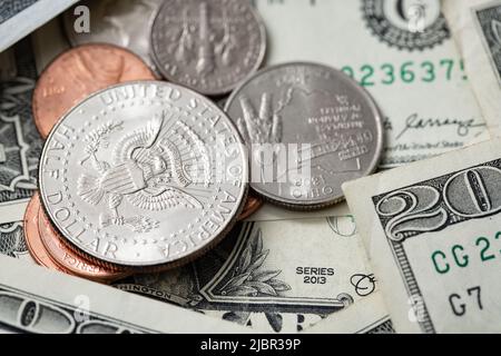 Half Dollar Coin on smaller coins surrounded by Dollar Banknotes. US Economy and Currency. Pile of Cash Money Stock Photo