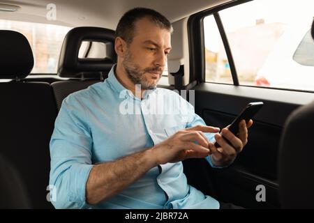Man Using Smartphone Sitting In Passenger Seat Of Car Stock Photo