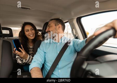 Couple Using Car Navigation App On Smartphone Sitting In Automobile Stock Photo