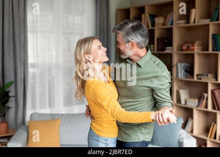 Romantic Middle Aged Couple Dancing Together In Living Room Interior Stock Photo