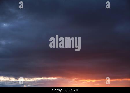 Thunderclouds with breaking rays sun at sunset Stock Photo