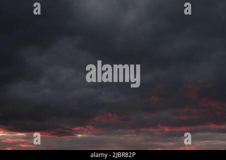Thunderclouds with breaking rays sun at sunset Stock Photo