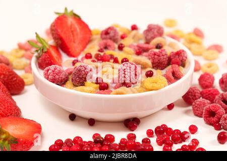 Corn rings with milk in a plate with berries and fruits, side view on a white background. The concept of quick breakfast cereals Stock Photo