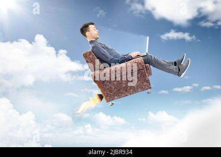 Man using a laptop computer is flying through the sky Stock Photo