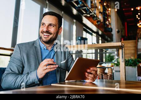 Portrait of young successful businessman with digital device working in corporate business office Stock Photo
