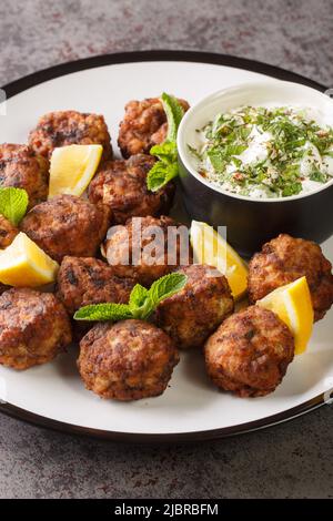 Greek Traditional Meatballs Keftedakia served with Tzatziki sauce closeup in the plate on the table. Vertical Stock Photo