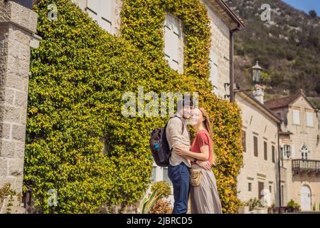 Happy couple in love man and woman tourists enjoying Colorful street in Old town of Perast on a sunny day, Montenegro. Travel to Montenegro concept Stock Photo