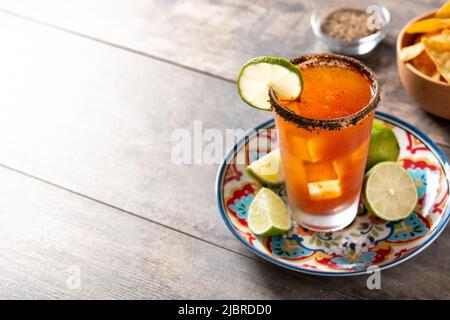 Homemade michelada cocktail with beer, lime juice,hot sauce,salted rim and tomato juice on wooden table Stock Photo