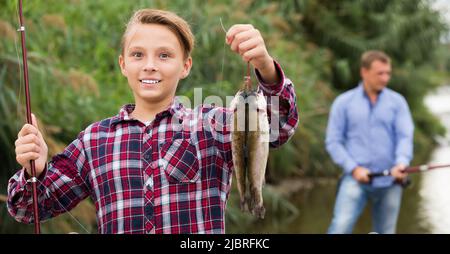 Close-up of a teenage boy holding a fishing rod - Stock Photo