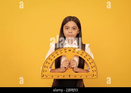 serious child in school uniform hold mathematics protractor for measuring, high school Stock Photo