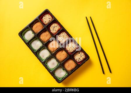 Japanese mochi dessert in a plastic box on a yellow background Stock Photo