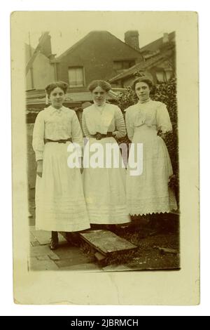 Original Titanic era portrait postcard of 3 attractive teenage girls, one called Rose, posing together outside in a garden, wearing white summer dresses, posted 8 August 1912, Bristol, U.K. Stock Photo
