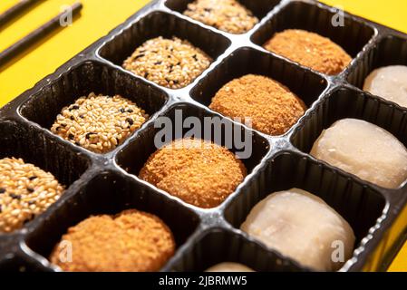 Japanese dessert packaged set on a yellow background. Japanese ice cream Mochi in rice dough. Traditional Japanese dessert on a yellow background. Stock Photo