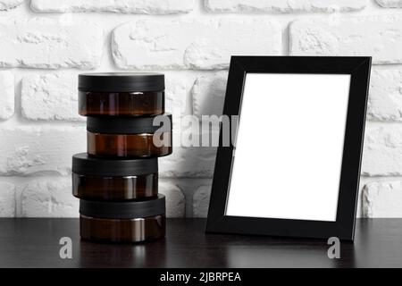 Skincare containers and black photo frame against white brick wall Stock Photo