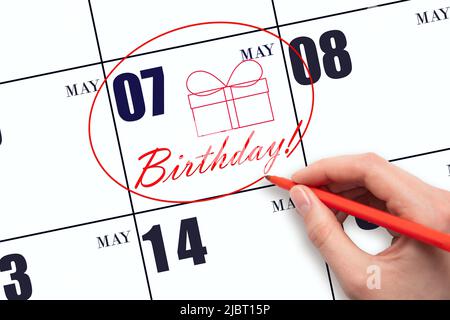 7th day of May. The hand circles the date on the calendar 7 May, draws a gift box and writes the text Birthday. Holiday. Spring month, day of the year Stock Photo