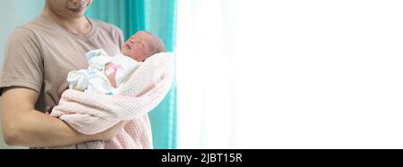 Father holding his newborn baby daughter in room close up on baby face Stock Photo