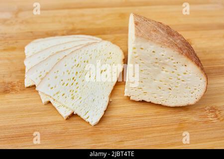 homemade smoked cheese sliced on a wooden board Stock Photo