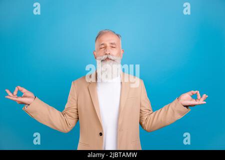 Portrait of handsome elegant dreamy grey-haired man meditating isolated over bright blue color background Stock Photo