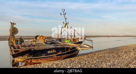 France, Somme, Le Hourdel, this trawler could not return to the port of Le Hourdel because of the low tide which did not offer enough depth for its draft; it had to run aground on the pebble beach to wait for the return of the tide. It is a boat equipped to fish for shrimp by scraping the bottom with nets Stock Photo