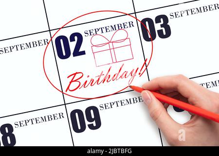 2nd day of September. The hand circles the date on the calendar 2 September , draws a gift box and writes the text Birthday. Holiday. Autumn month, da Stock Photo