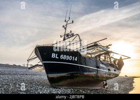 France, Somme, Le Hourdel, this trawler could not return to the port of Le Hourdel because of the low tide which did not offer enough depth for its draft; it had to run aground on the pebble beach to wait for the return of the tide. It is a boat equipped to fish for shrimp by scraping the bottom with nets Stock Photo