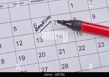 Deadline word written on the calendar by black marker top view. Black highlighter on the calendar. Stock Photo
