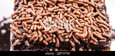 close up slice of carrot cake with creamy chocolate icing and sprinkles, typical of Brazilian June festivals Stock Photo
