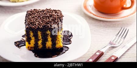 carrot cake with chocolate icing dripping on plate, served with latte and other sweets, bakery sweet, brazilian afternoon boat Stock Photo